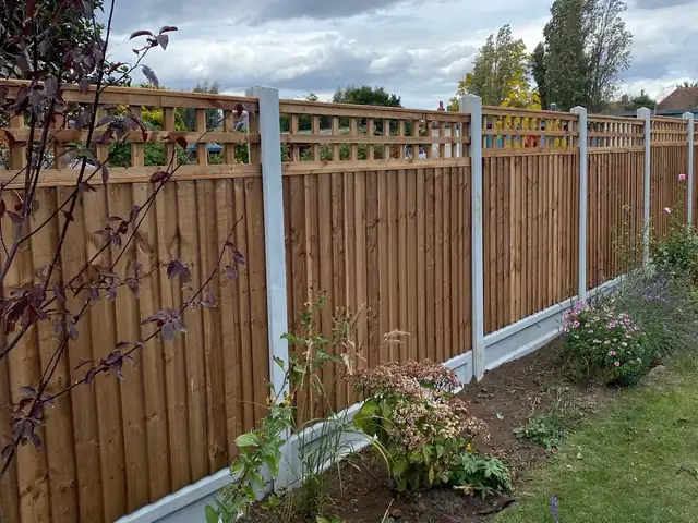 Close-board fence with concrete posts, gravel boards and trellis along a planted border